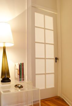 a white table with a lamp on top of it next to a door and window