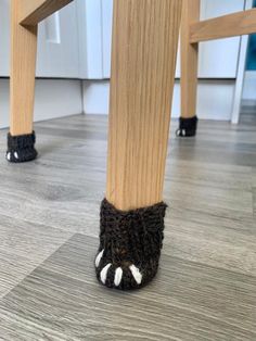 a pair of feet with black and white socks underneath a wooden table in a kitchen