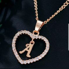 a heart shaped initial necklace with the letter a in it's center on a black surface