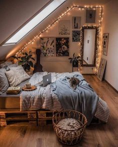 an attic bedroom is decorated with string lights and bedding, while a cat sits on the bed