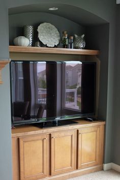 a flat screen tv sitting on top of a wooden entertainment center in a living room