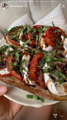 a person holding up a piece of bread with tomatoes and mozzarella on it