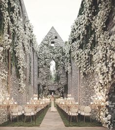 an outdoor wedding venue with flowers and greenery on the walls, decorated with candles