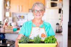 an older woman holding a potted plant in the kitchen