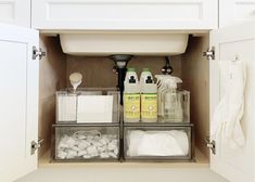 the kitchen sink is open to reveal two containers with soaps and other cleaning products