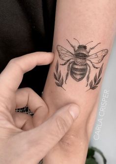 a woman's arm with a black and white tattoo of a bee on it