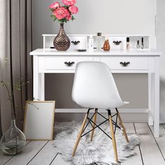 a white desk with two drawers and a mirror on top of it next to a vase filled with pink flowers