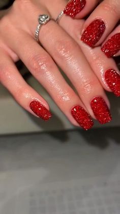 a woman's hand with red glitter on it and a ring on her finger