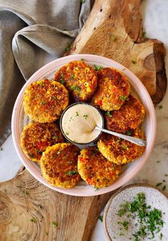 crab cakes on a plate with dipping sauce and parsley sprinkled around the edges