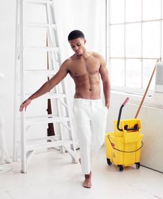 a man in white pants is standing next to a yellow mop