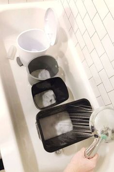 a person is washing dishes in a bathtub with soap and water on the trays