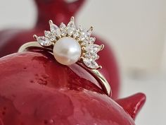 a pearl and diamond ring sitting on top of a red object