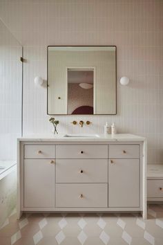 a bathroom with a large mirror above the sink and white cabinetry, along with two stools