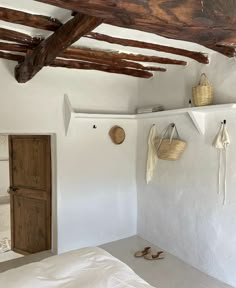 a bedroom with white walls and wooden beams on the ceiling is decorated in natural materials