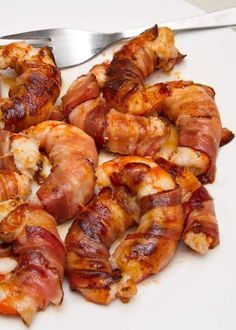 bacon wrapped shrimp on a white plate with a fork