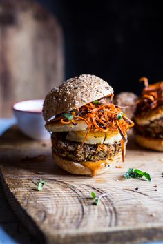 two burgers sitting on top of a wooden cutting board