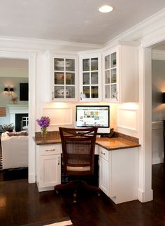 a home office with white cabinets and wood floors