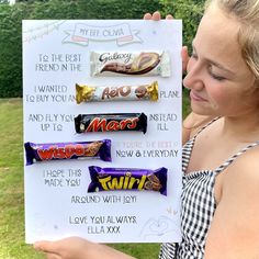 a girl holding up a sign with candy bars on it