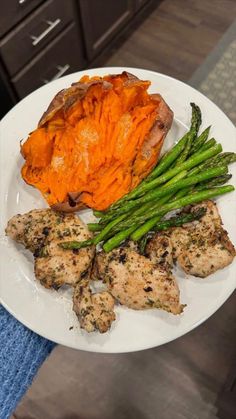 a white plate topped with chicken, asparagus and sweet potato