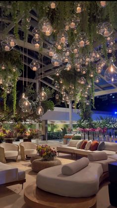 a large room with couches, tables and hanging lights in the middle of it