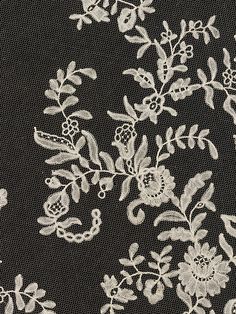 white lace on black fabric with flowers and leaves in the center, closeup view