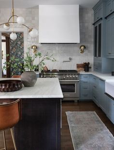 a kitchen with blue cabinets and marble counter tops, along with an island in the middle