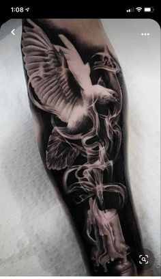 a man's leg with a black and white tattoo design on it, depicting a bird