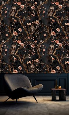 the wallpaper is decorated with pink flowers and black branches, while an armchair sits in front of it