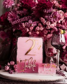 the table is set with pink flowers and wine glasses