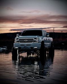 a truck is parked in the water at sunset