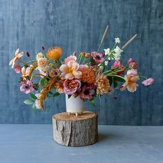 a vase filled with flowers sitting on top of a tree stump