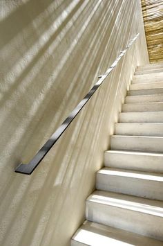 there is a long metal stair rail on the side of a wall next to some stairs