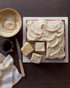 a cake with white frosting sitting on top of a cutting board next to a knife