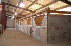 the inside of a horse barn with stalls