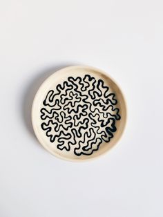 a black and white plate on a white surface with an abstract design in the center