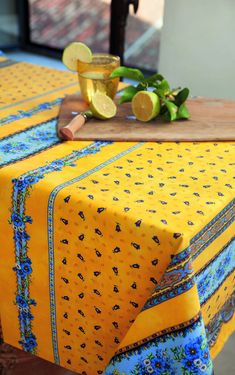 a yellow table cloth with blue flowers and lemons on it