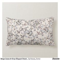 a white pillow with blue and grey floral print on the front, sitting against a wall