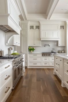 a large kitchen with white cabinets and wood flooring, along with stainless steel appliances