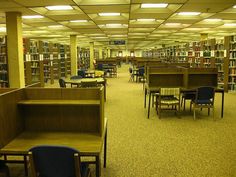 a library filled with lots of books and tables next to each other on top of carpeted flooring