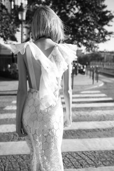 black and white photograph of woman in dress walking down the street with her back to the camera