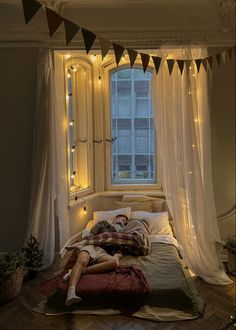 a man laying on top of a bed under a window