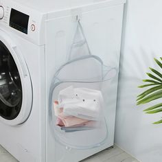 a washing machine that has some items in the basket on it and is next to a potted plant