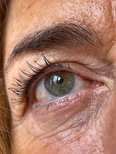 a woman's blue eye with long lashes and freckles on her face