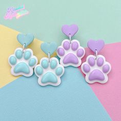 three pairs of earrings with paw prints and hearts on them, sitting next to each other