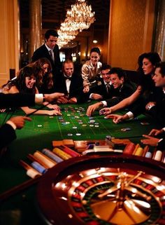 a group of people sitting around a green table playing roulejack in a casino