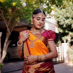 a woman in an orange and red sari is looking down at her necklaces