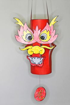 a red paper lantern with a dragon face on it's side and a chinese coin hanging from the front