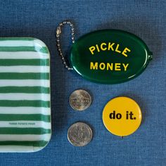 the pickle money is sitting next to two coins and a plastic tray on a blue surface