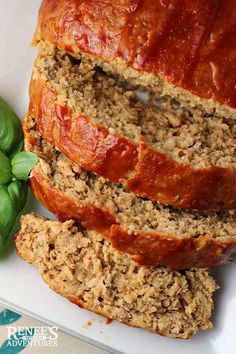 sliced meatloaf on a white plate with basil