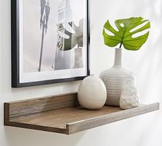 two white vases sitting on top of a wooden shelf next to a framed photograph